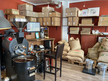 Laden Sie das Bild in den Galerie-Viewer, Großer Kaffeeröster mit Kaffeesäcken im Hintergrund