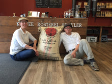 Laden Sie das Bild in den Galerie-Viewer, Raphaela und Michael vor einem Kaffeesack in der Kaffee Rösterei Schuler